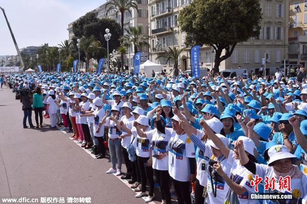當?shù)貢r間2015年5月8日，法國尼斯，中國某集團慶祝公司20周年紀念日，該集團半數(shù)員工約6400人獲得4天假期，分別在巴黎和尼斯旅游兩天。圖為公司員工在尼斯的海濱大道慶祝。