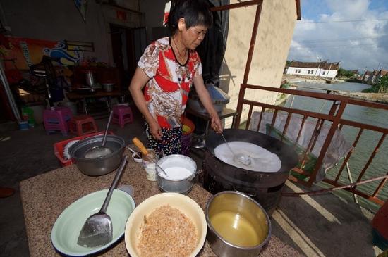 　5月27日，埭美村一位經(jīng)營小吃店的村民在為游客做當?shù)孛朗场板佭吅? longdesc=