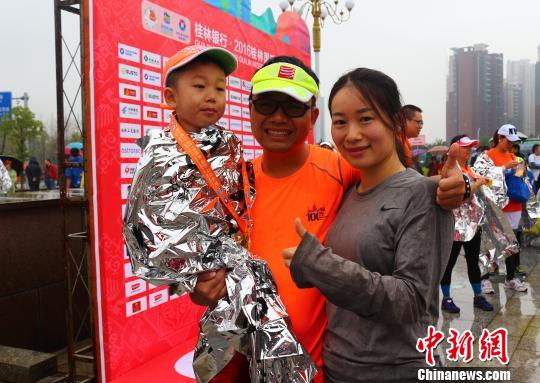 來自廣州的李強(qiáng)夫婦用兒童車，載著4歲的兒子，一家三口完成了在桂林舉行的半程馬拉松比賽。　歐惠蘭 攝