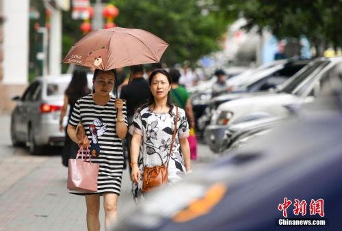 新疆烏魯木齊市街頭，民眾打傘抵擋高溫天氣。