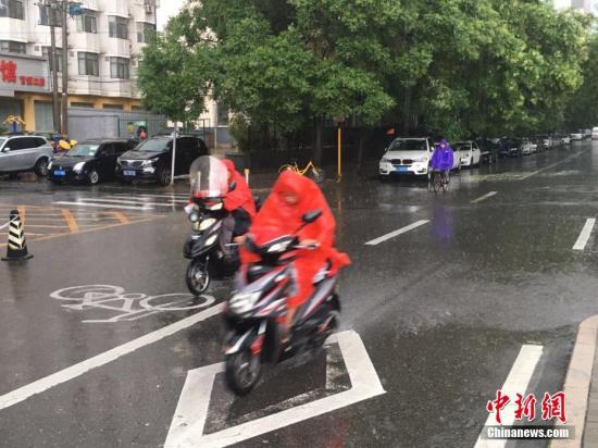 6月23日清晨，北京降雨持續(xù)，并出現(xiàn)了短時(shí)大雨。據(jù)北京市氣象局官方微博消息，北京市氣象臺(tái)今日6時(shí)發(fā)布：今天白天小到中雨并伴有雷電，傍晚局地伴有短時(shí)大風(fēng)或冰雹，北轉(zhuǎn)東風(fēng)2、3級(jí)，最高氣溫24℃；夜間有雷陣雨，東轉(zhuǎn)北風(fēng)2、3級(jí)，最低氣溫19℃。圖為北京阜成路，市民雨中騎行。 <a target='_blank' href='http://www.chinanews.com/' >中新網(wǎng)</a>記者 富宇 攝