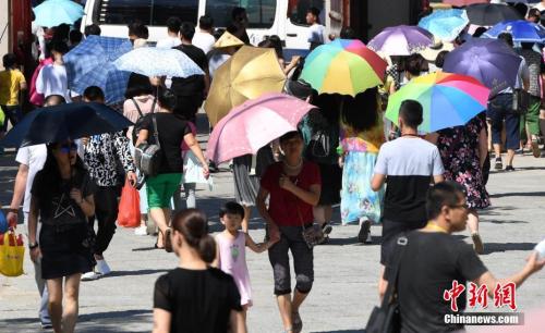 7月12日，廈門一景點(diǎn)游客們紛紛打起傘遮擋烈日。張斌 攝