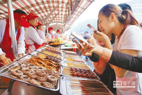 北京一“蟲子宴”攤位，擺滿串蛇、蜈蚣、螞蚱、蜘蛛等，不少食客拿出手機(jī)拍照。（臺(tái)灣中時(shí)電子報(bào)）