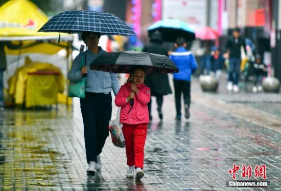 資料圖：9月24日，新疆烏魯木齊市降下秋雨，外出民眾打著雨傘快步前行。 <a target='_blank' href='http://www.chinanews.com/'>中新社</a>記者 劉新 攝