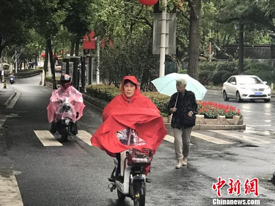 11日，南京迎來降溫降雨。圖為市民披上雨衣出行?！铑伌?攝