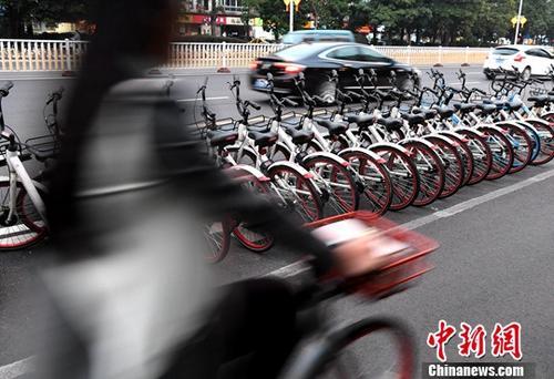 資料圖：路人騎著共享單車經(jīng)過“車堆”。<a target='_blank' href='http://www.chinanews.com/'>中新社</a>記者 張斌 攝