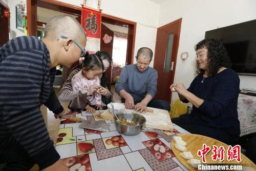 圖為彭秀芳“一家四口”包餃子。(抱著玲玲的是福利院工作人員) 胡貴龍 攝