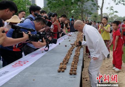 黎偉軍手劈核桃現(xiàn)場(chǎng)吸引不少人圍觀?！〕叹皞?攝