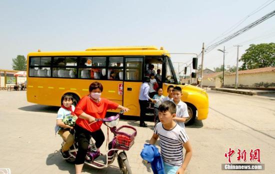 資料圖：學(xué)生家長接送從校車上下來的學(xué)生。 張道正 攝