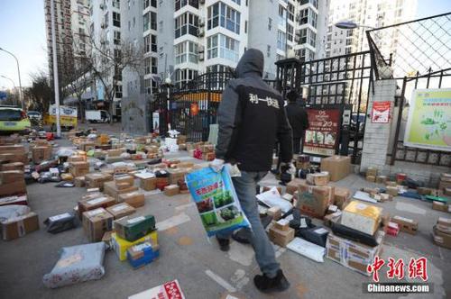 3月3日，北京朝陽區(qū)一小區(qū)門口，快遞員為居民查找搬運快遞物品。受疫情影響，許多市民“宅”在家中，網(wǎng)購成為消費主流，而線上下單量也隨之呈現(xiàn)爆發(fā)式增長，不少小區(qū)門口出現(xiàn)快遞物品扎堆的現(xiàn)象。<a target='_blank' href='http://www.chinanews.com/'>中新社</a>記者 趙雋 攝